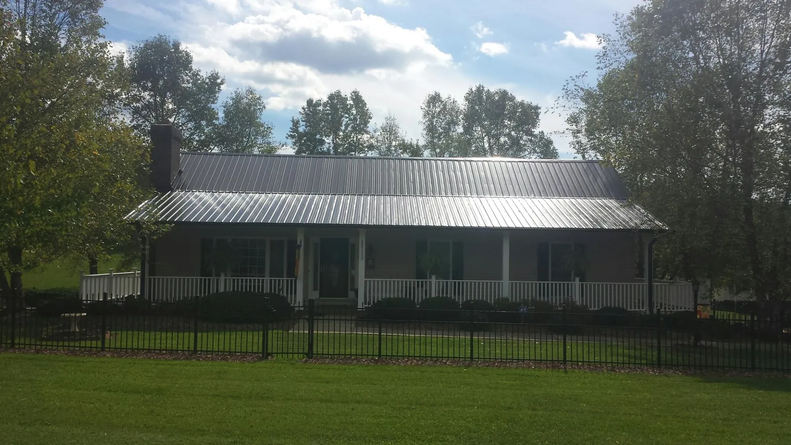 Gray metal roof on a brick ranch with a full width front porch — Gutter Guard Installation work by our crew in Hillsboro